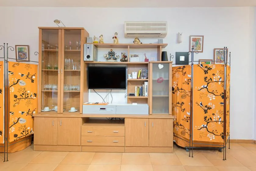 A living room with a wooden entertainment unit and orange folding screens.