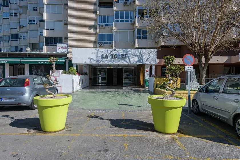 The entrance to an apartment building faces a paved area with large planters.