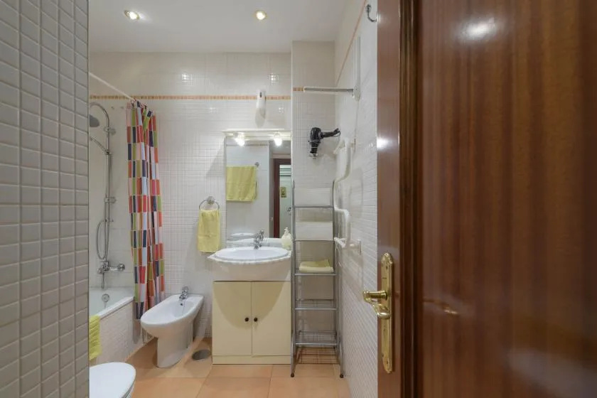 A tiled bathroom with a bathtub, sink, and colorful shower curtain.