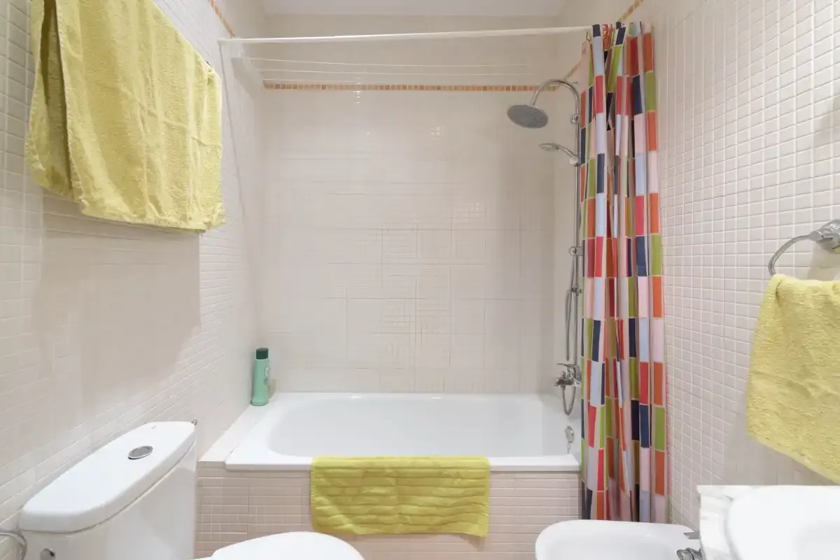 A tiled bathroom with a bathtub, shower, and colorful curtain.