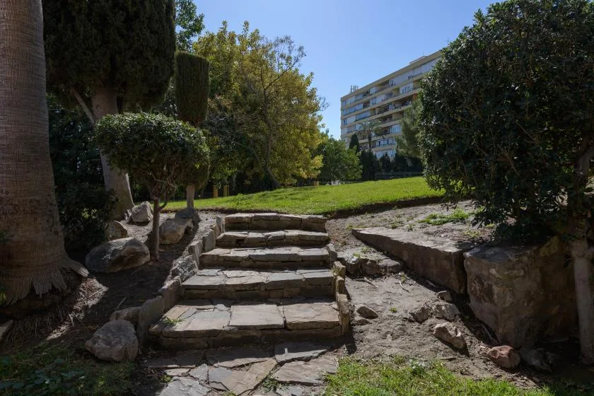 Stone steps lead up through a landscaped garden toward a modern building.
