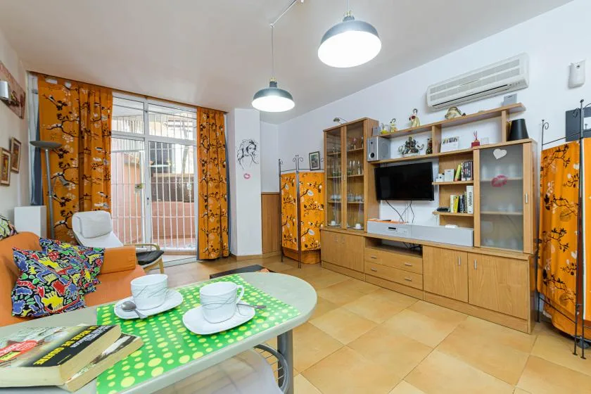 A living room with seating, a television, and a green patterned table.