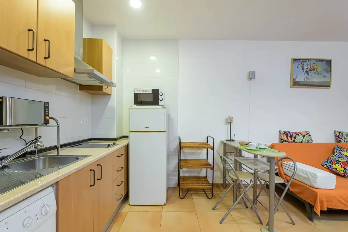 A compact kitchen and dining area with wooden cabinets and a table.