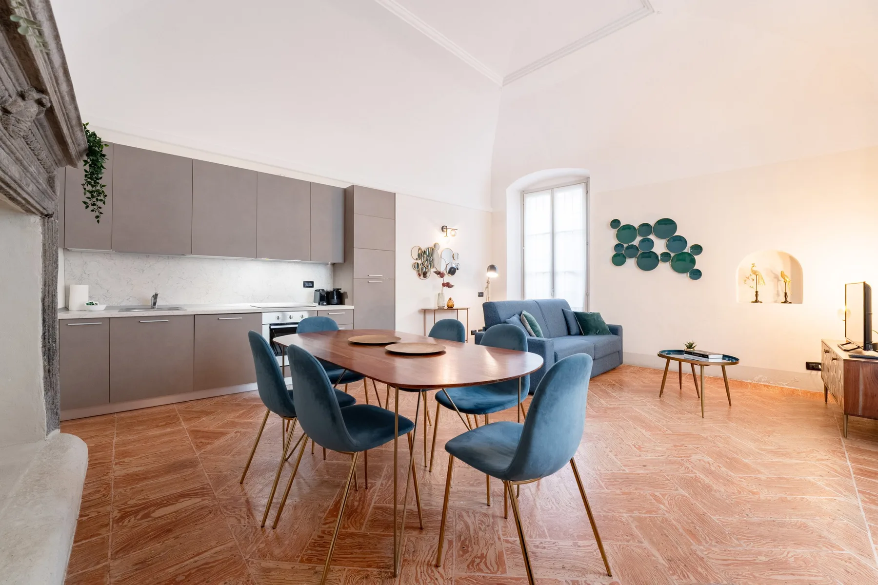 Una luminosa cocina-comedor de planta abierta tiene una mesa redonda y asientos azules.