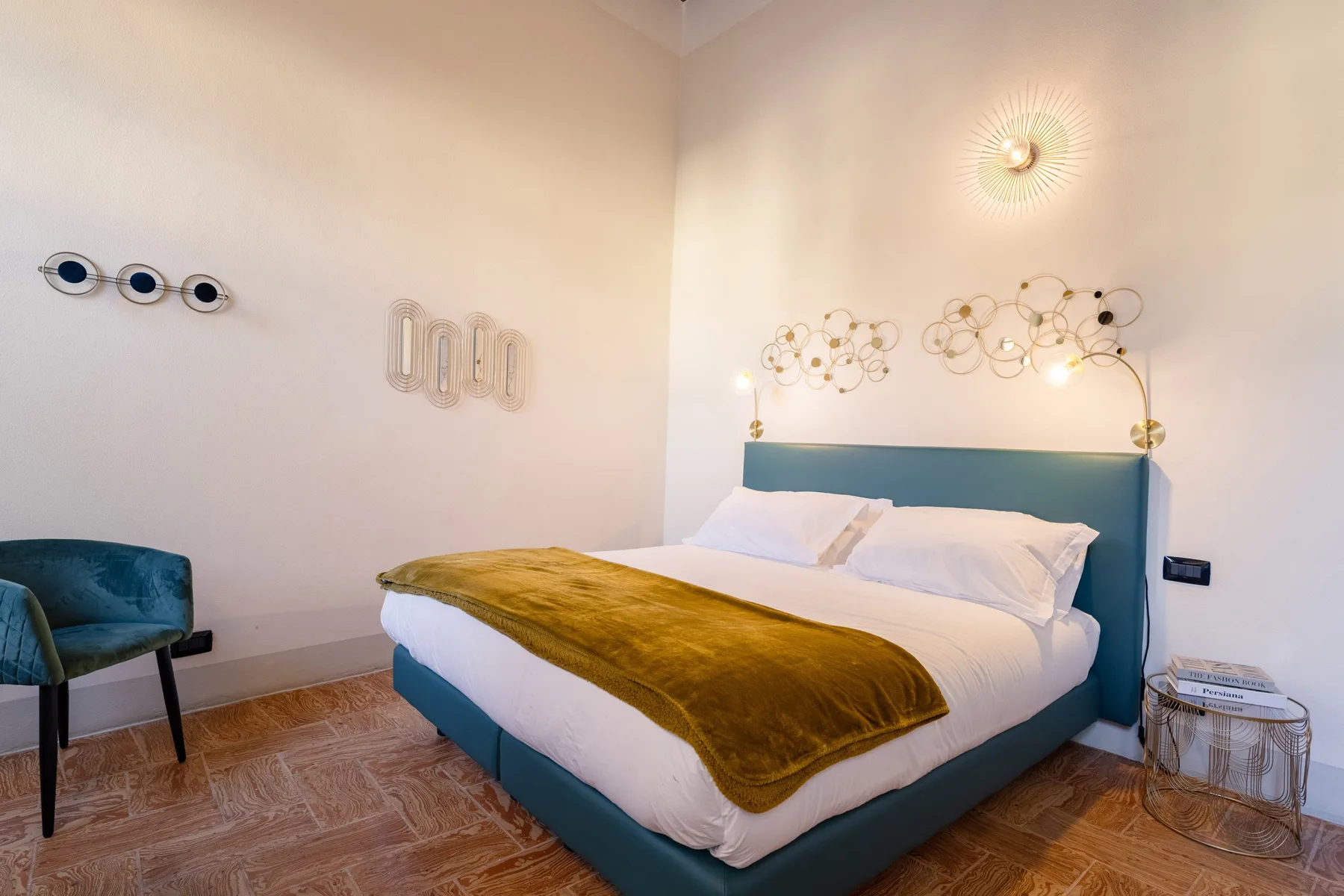 Un dormitorio con una cama color turquesa y arte decorativo en la pared.