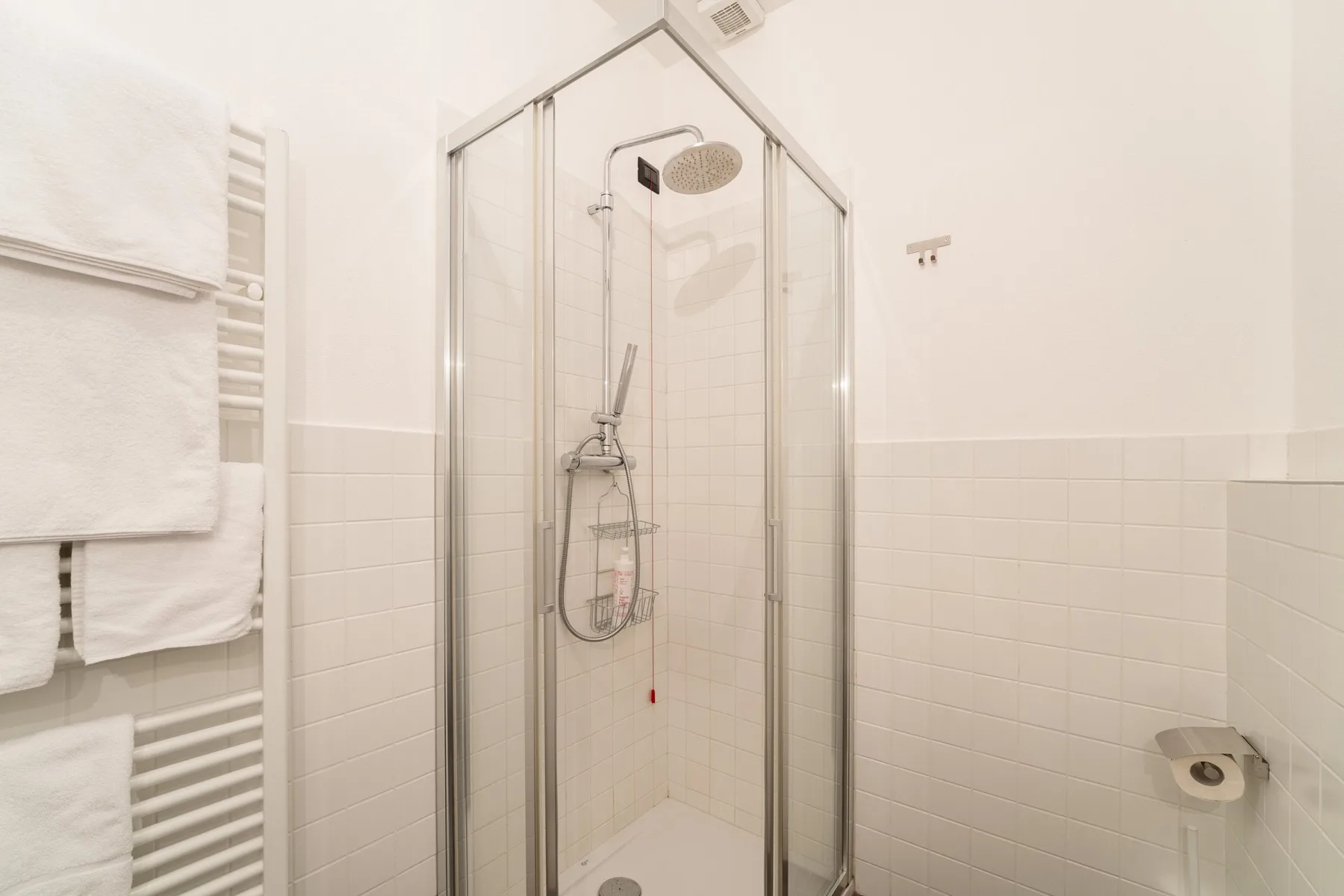 Un baño con azulejos, una ducha de vidrio y un toallero calefactable.