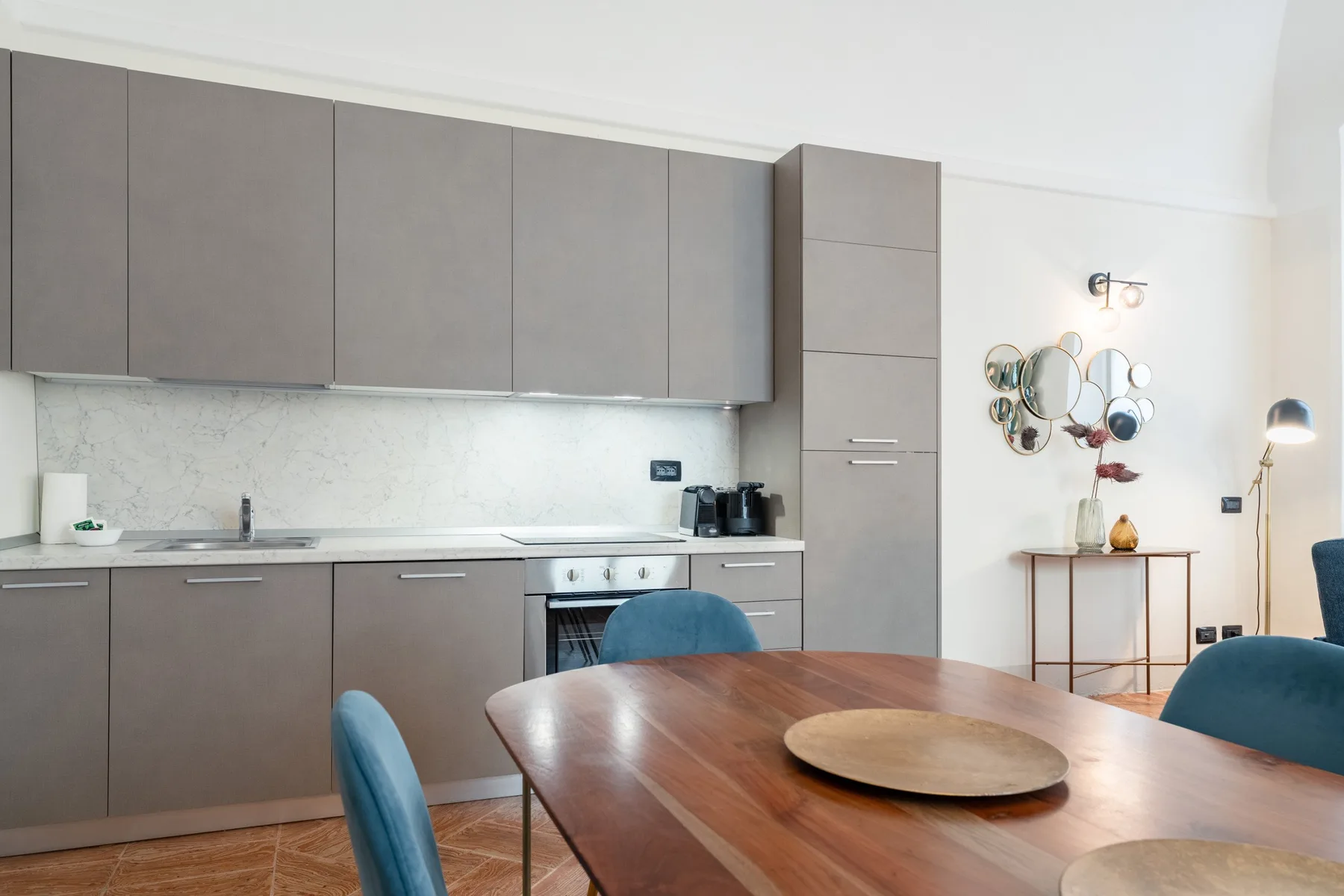 Una cocina moderna y comedor con armarios grises y una mesa de madera.