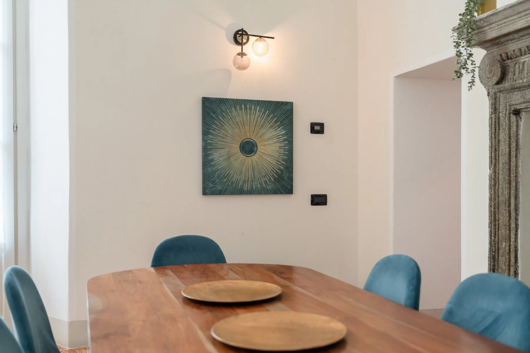 Un comedor con una mesa de madera y una obra enmarcada en la pared.