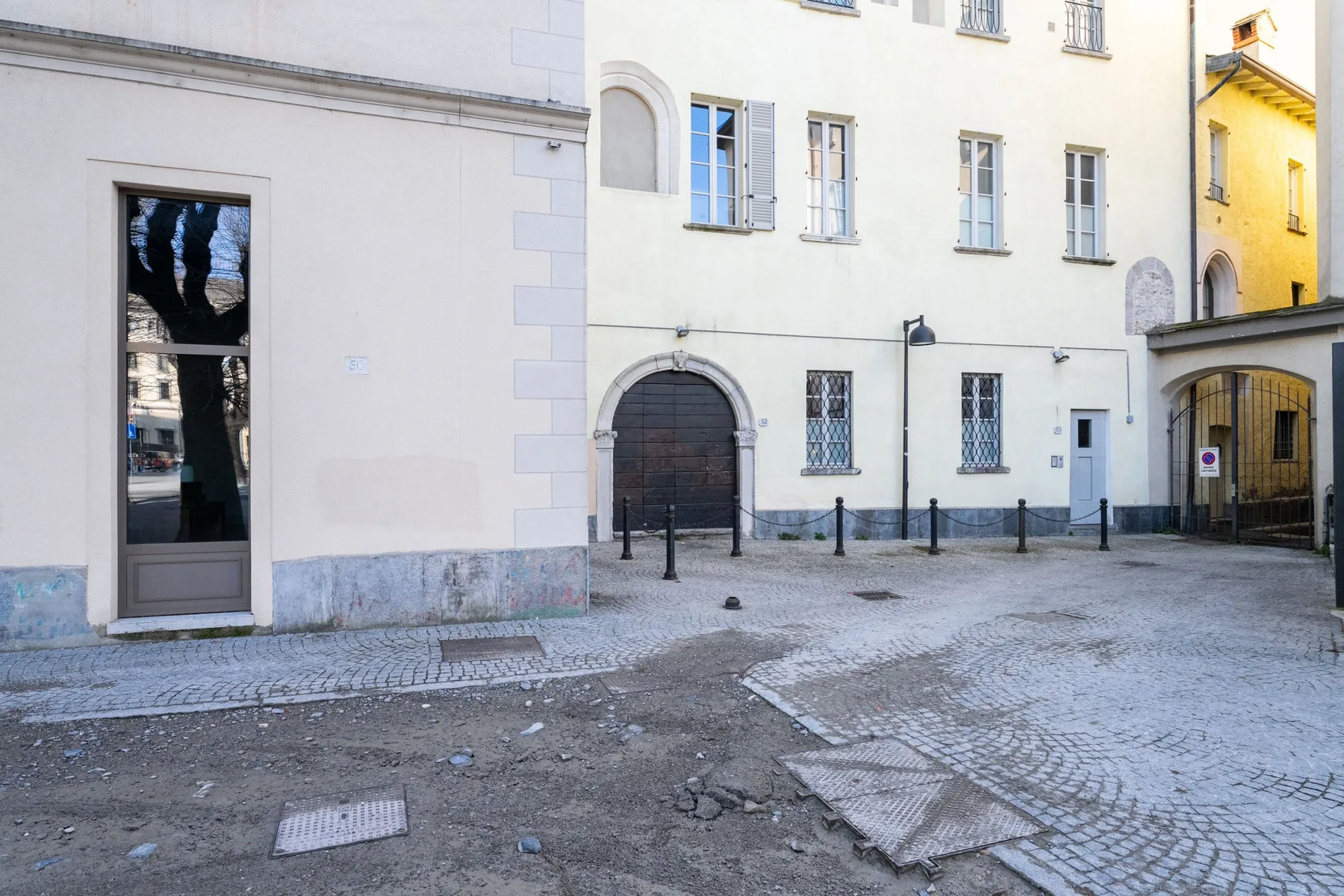 Un patio empedrado rodeado de edificios claros, con puertas arqueadas y ventanas.