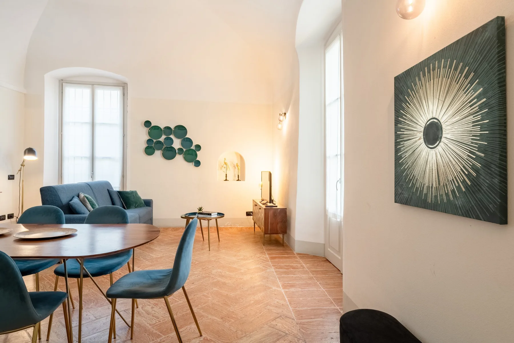 Una sala luminosa con asientos azules, una mesa redonda y arte en las paredes.