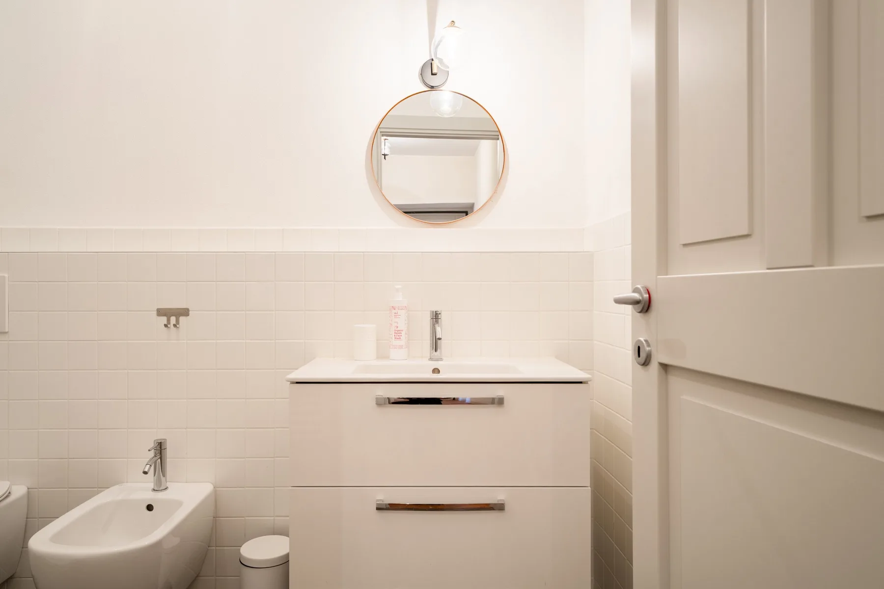 Un baño luminoso con lavabo, espejo y bidé.