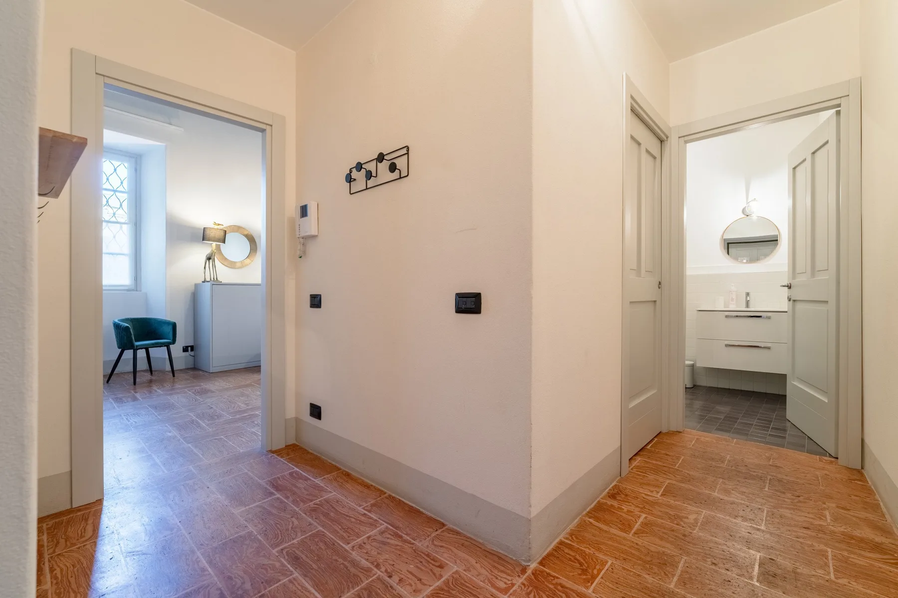 Un pasillo con suelo de baldosas da a una zona de estar y un lavabo.