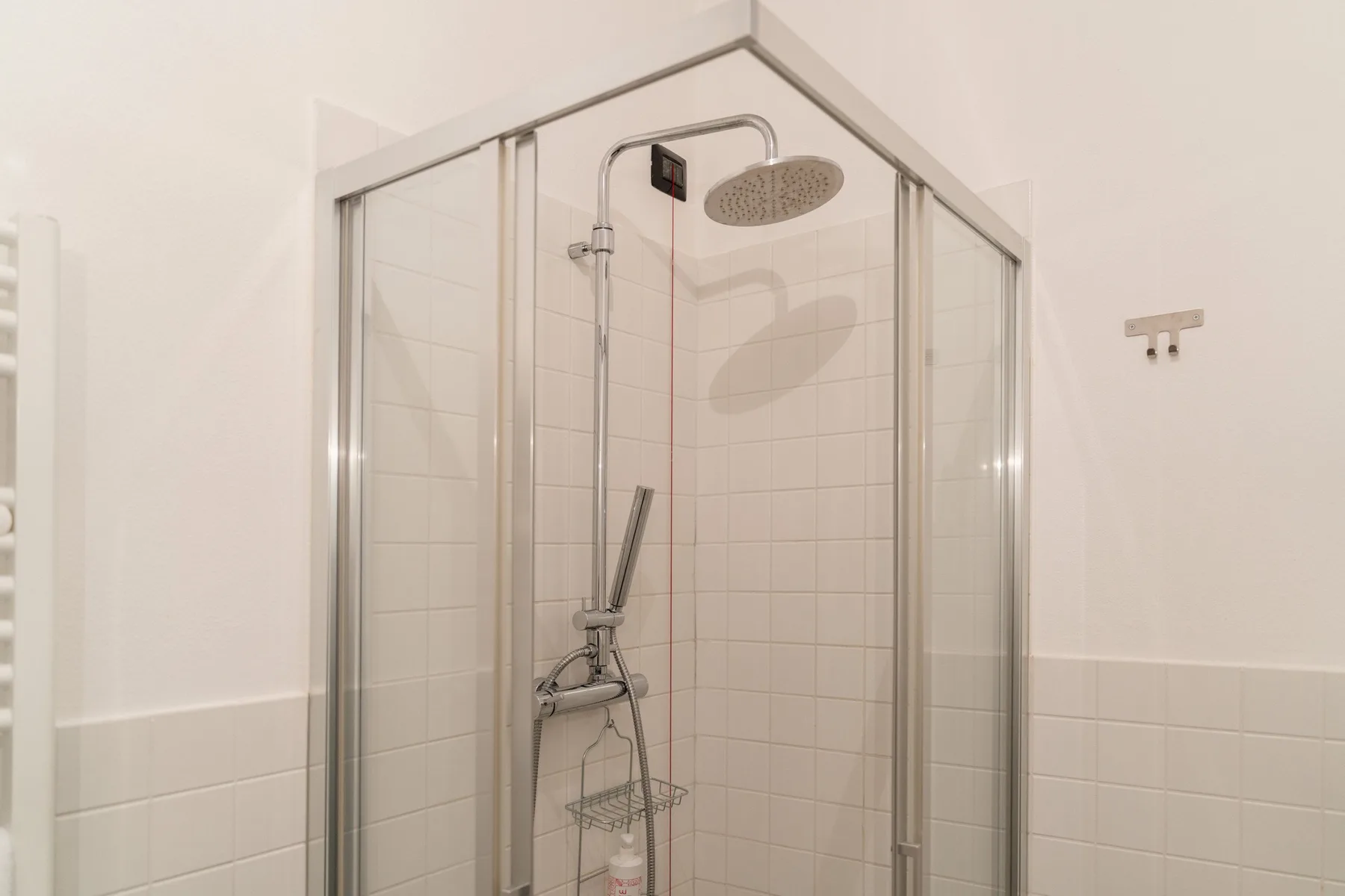 Una ducha de baño alicatada con rociador superior y ducha de mano.