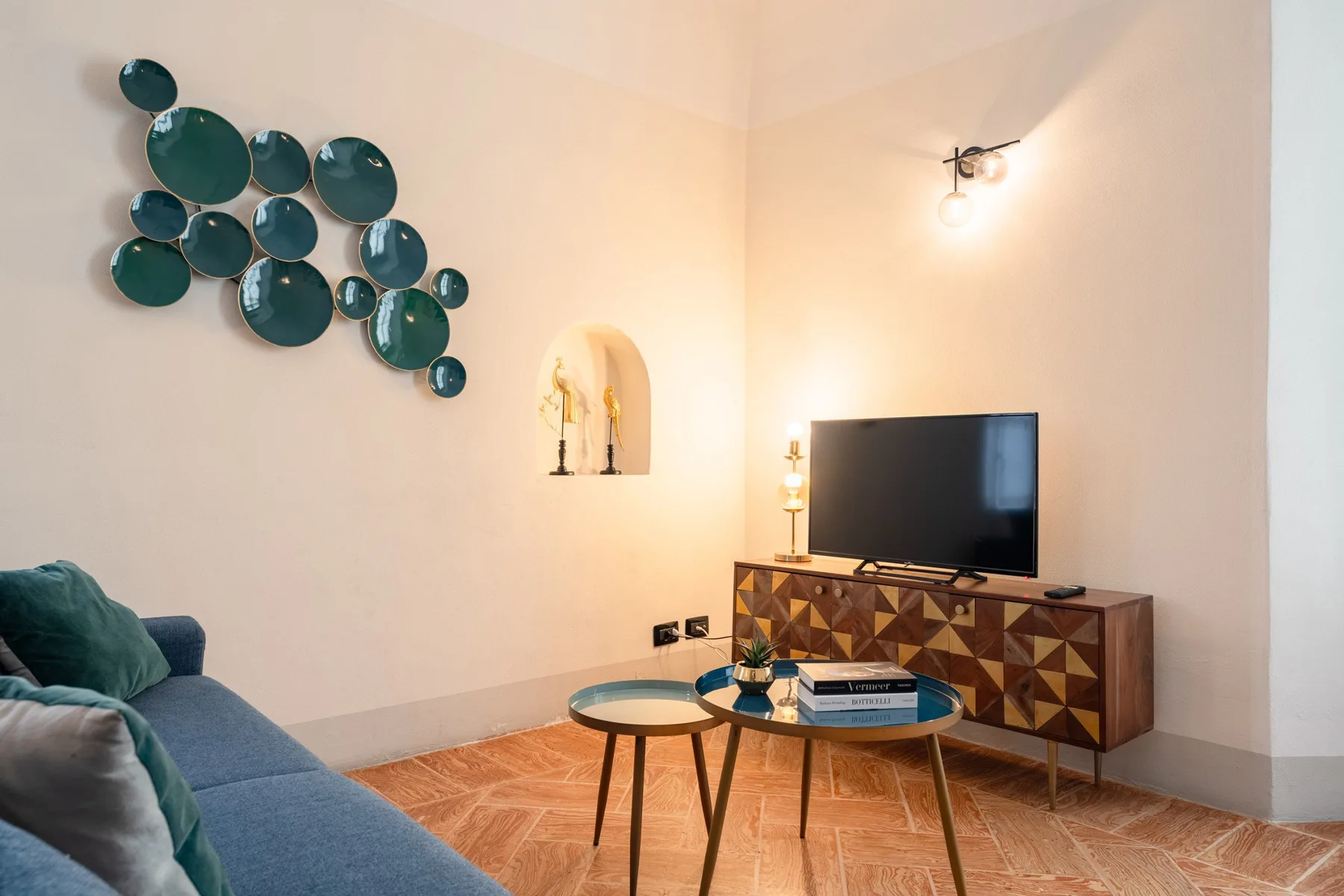 Una sala de estar con asientos, un televisor y arte decorativo en la pared.