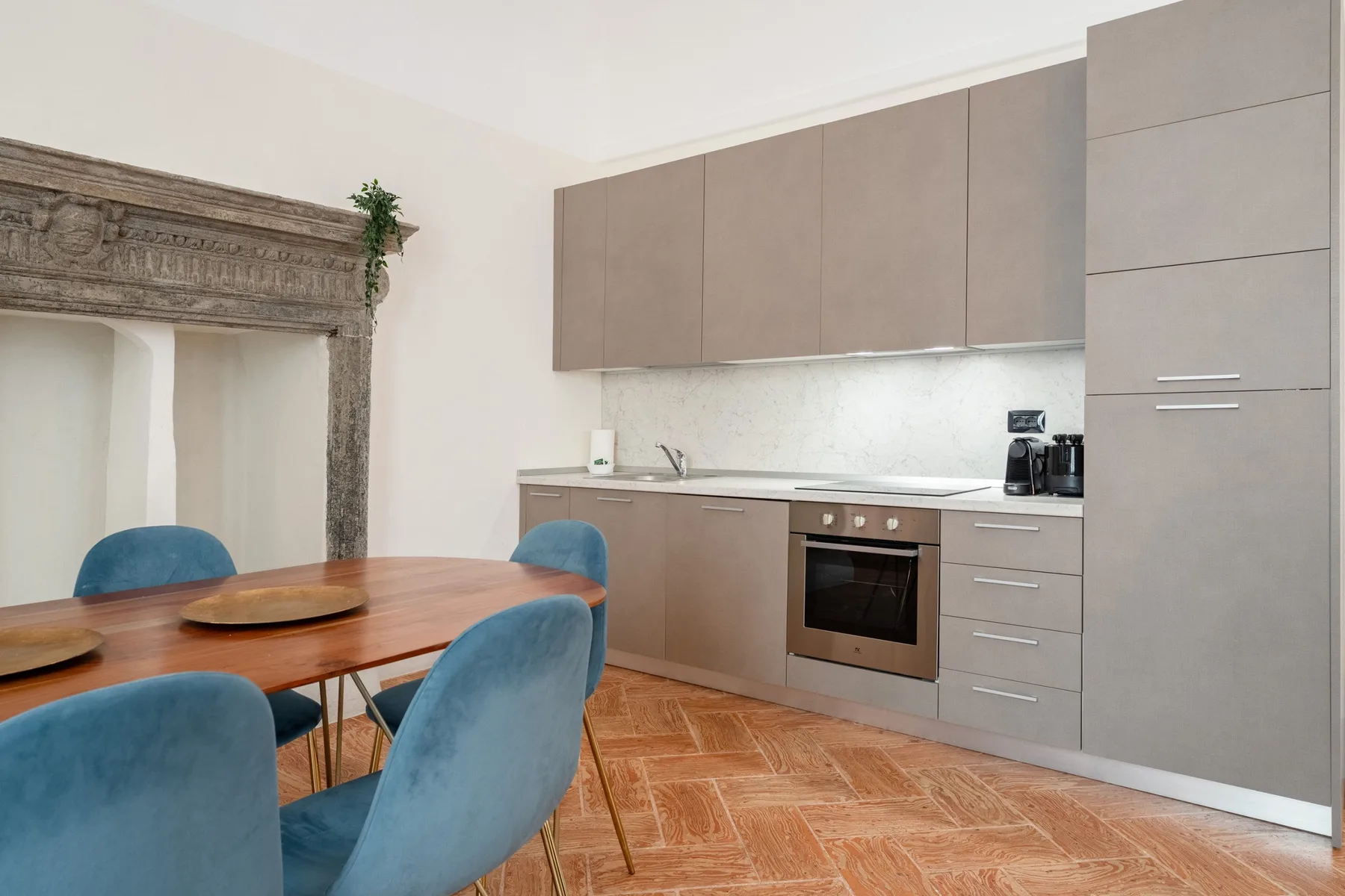 Un comedor con asientos azules junto a una cocina compacta.