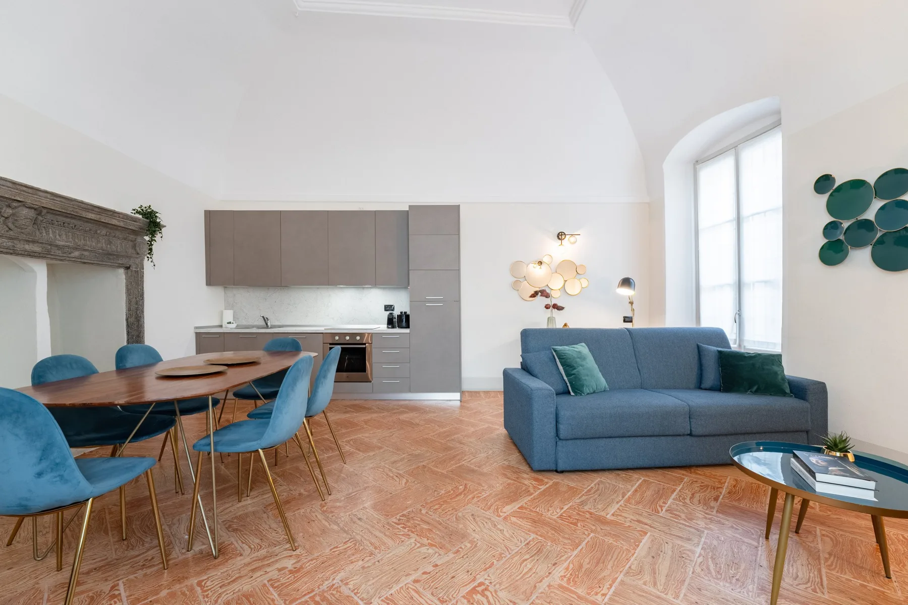 Una luminosa sala de estar y comedor diáfana, con un sofá azul y una cocina.