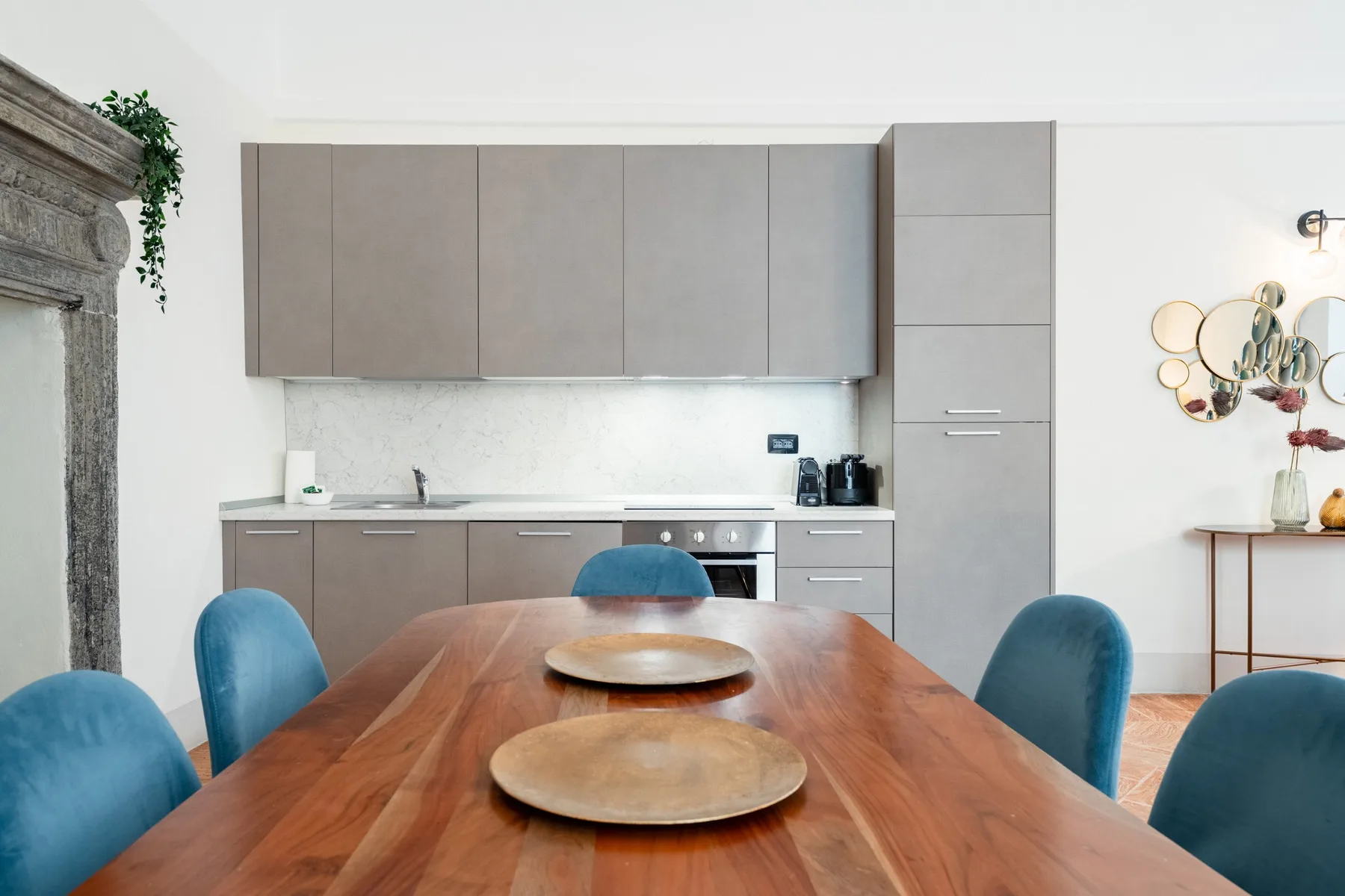 Una mesa de comedor con asientos azules frente a una cocina moderna.
