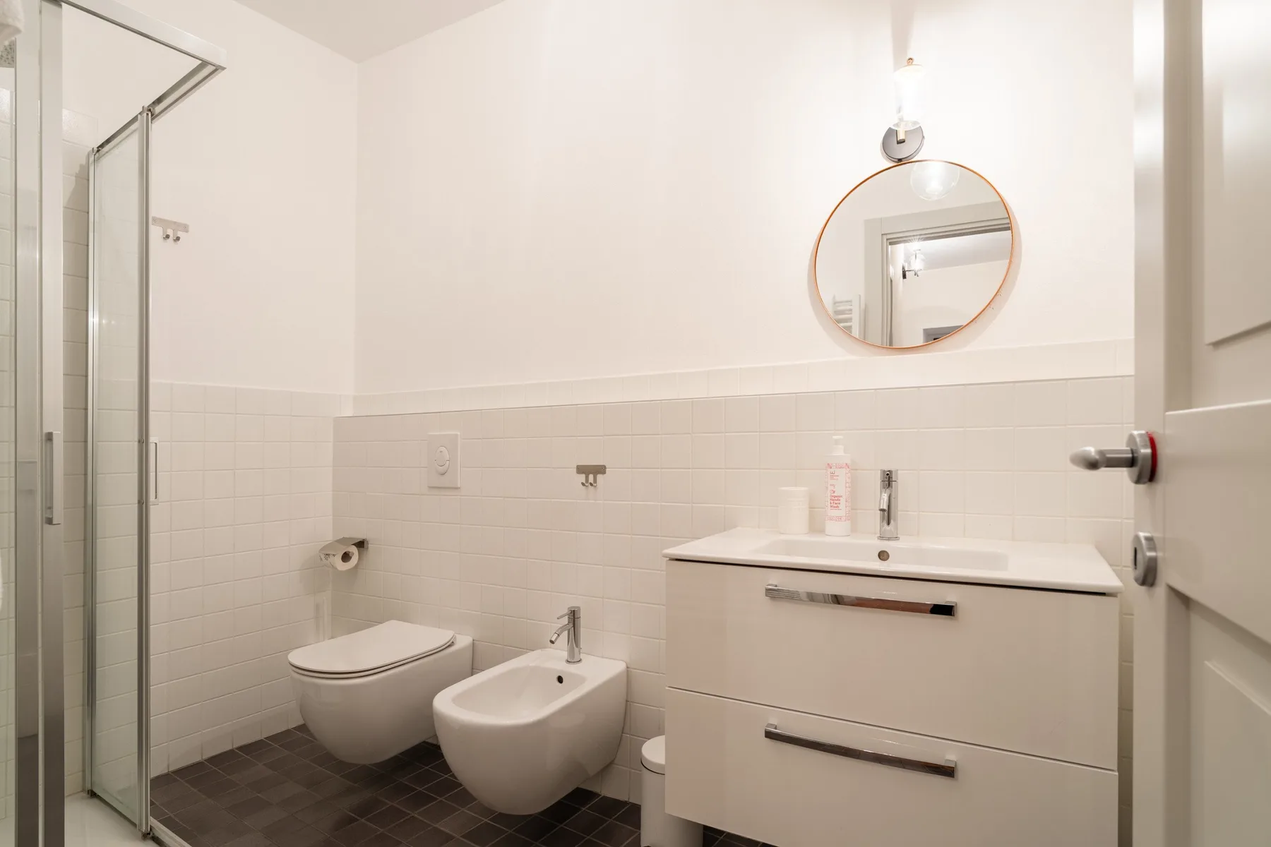 Un baño luminoso con lavabo, inodoro y ducha.
