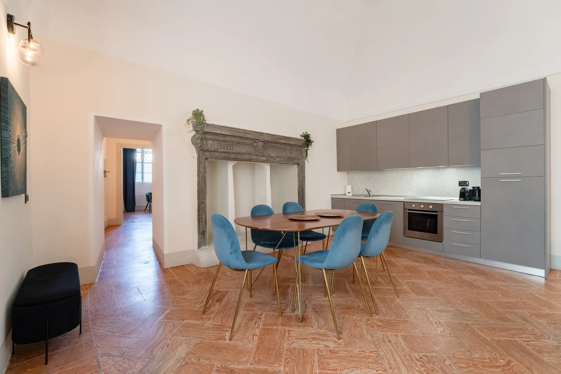 Comedor con una mesa y asientos azules junto a una cocina moderna.