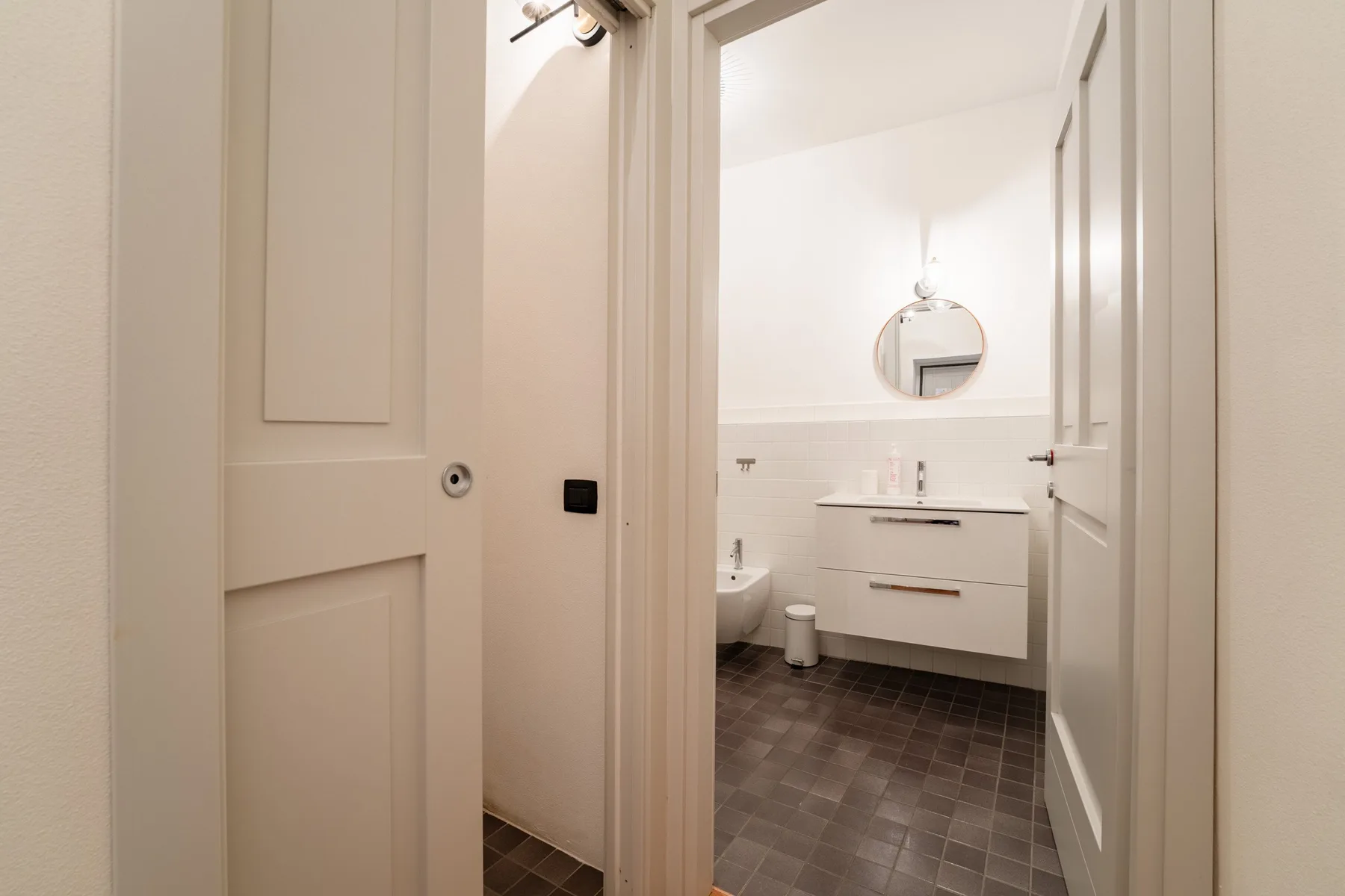 Un baño con un espejo sobre el lavabo y un suelo de baldosas.