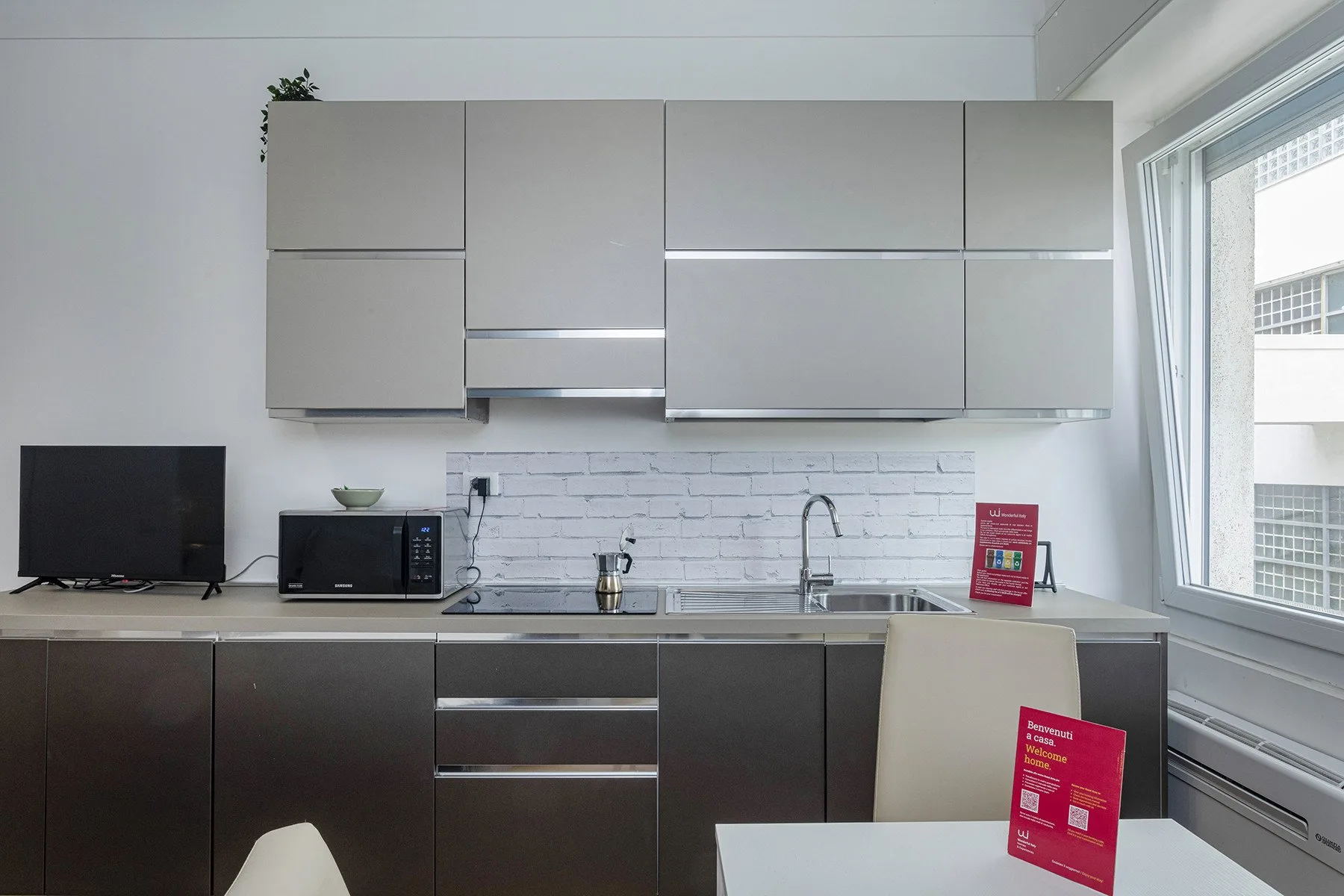 A modern kitchen with dark lower cabinets, a countertop, and a window.