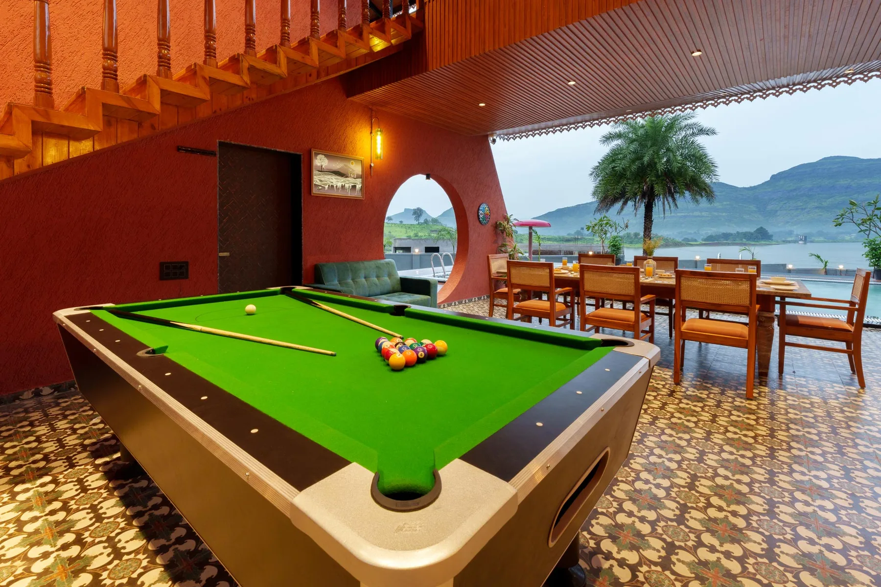 Una mesa de billar está junto a un comedor con vista al agua.