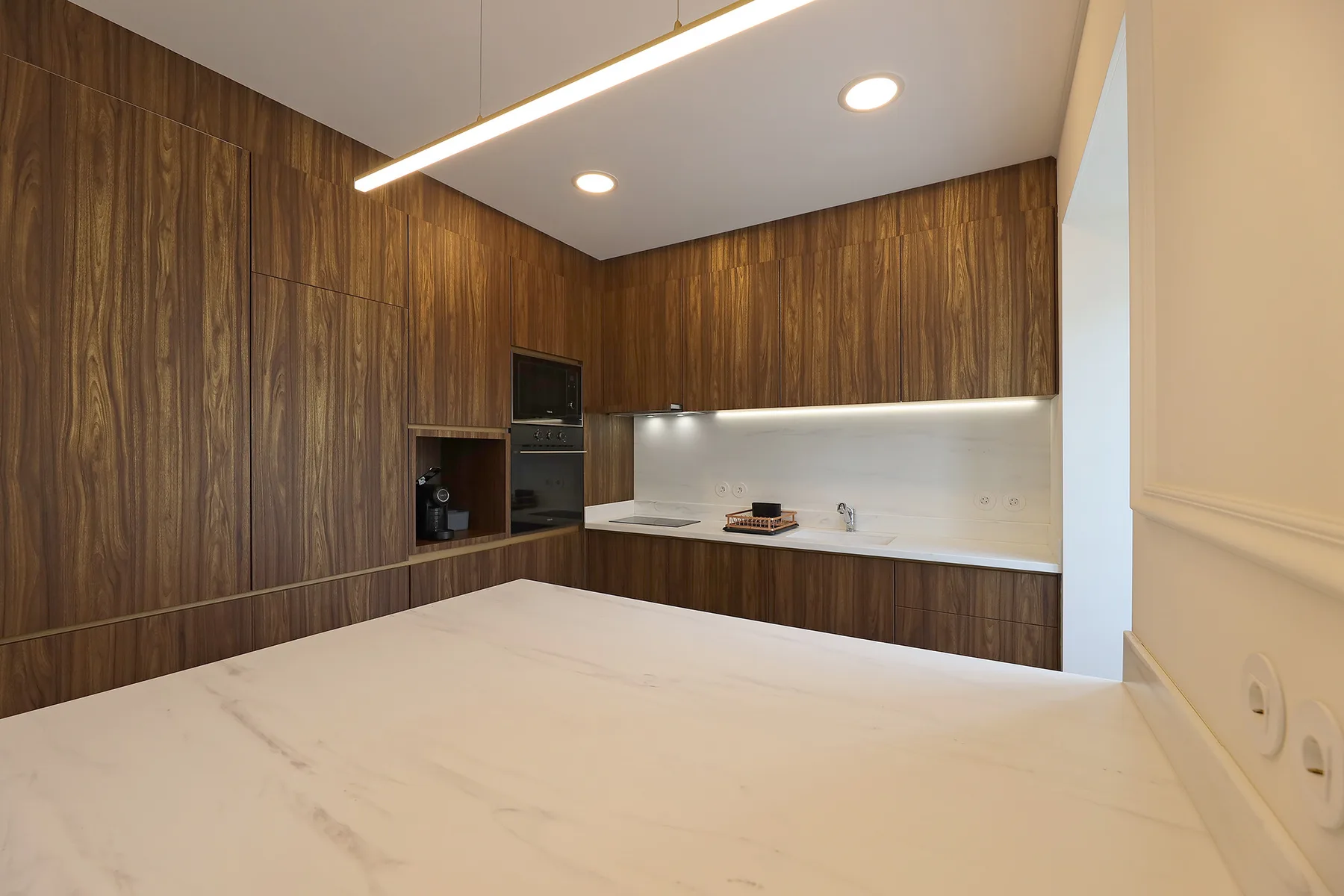 Una cocina moderna con armarios de madera oscura y una encimera clara.