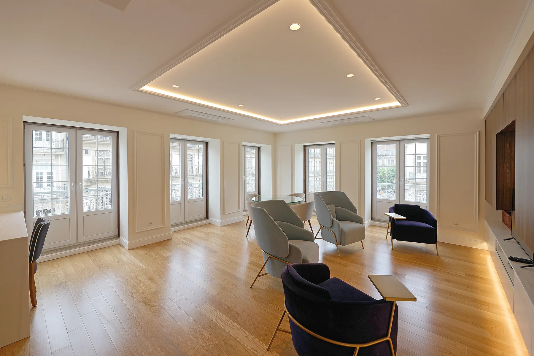 Una sala de estar luminosa con asientos junto a una mesa baja y grandes ventanas.