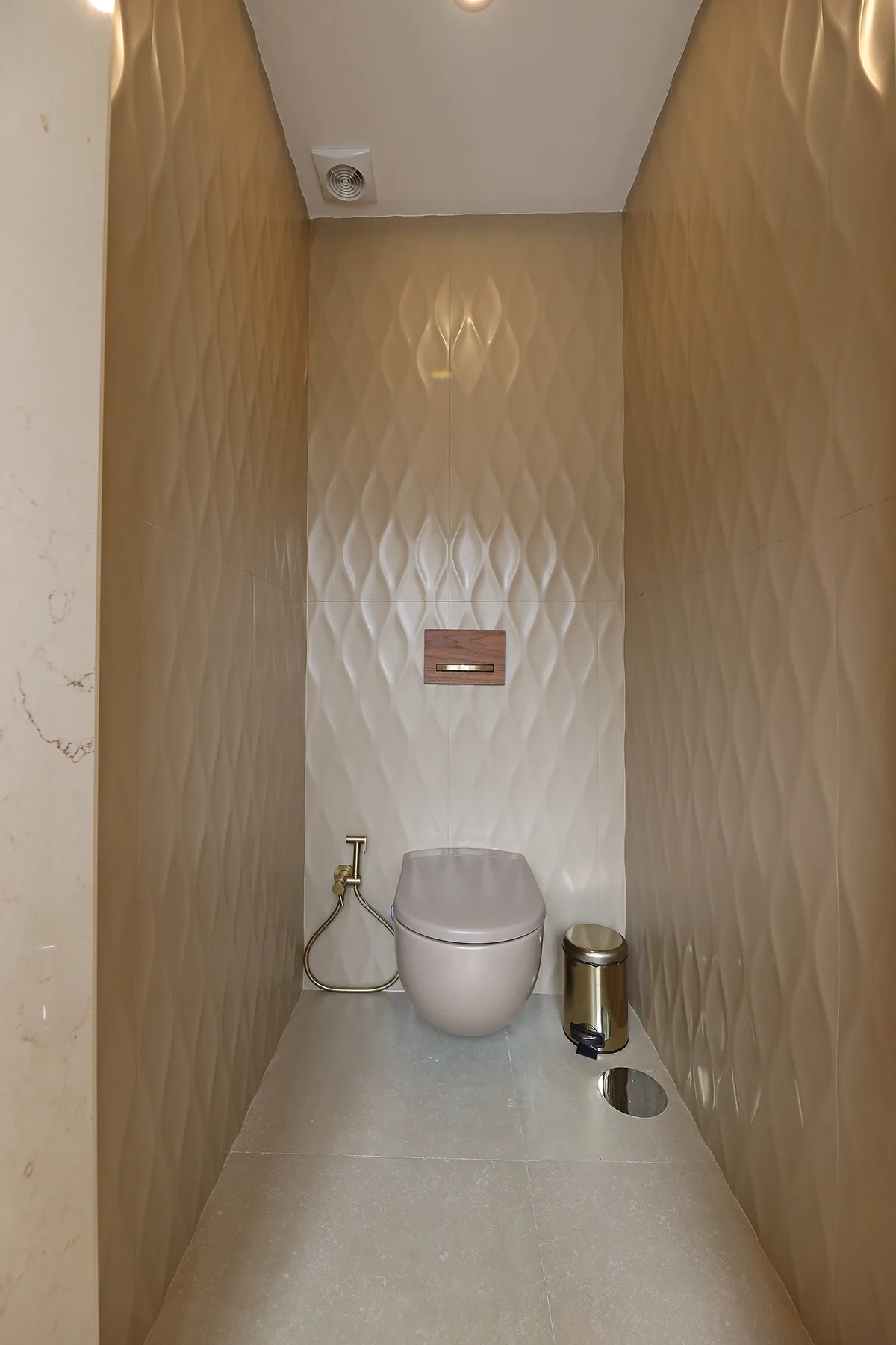 Un baño estrecho con un inodoro suspendido y paredes con textura.