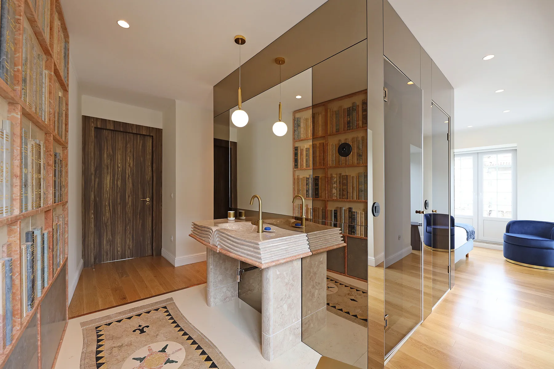 A bright apartment interior with a kitchen island and bookshelves beside a living area.