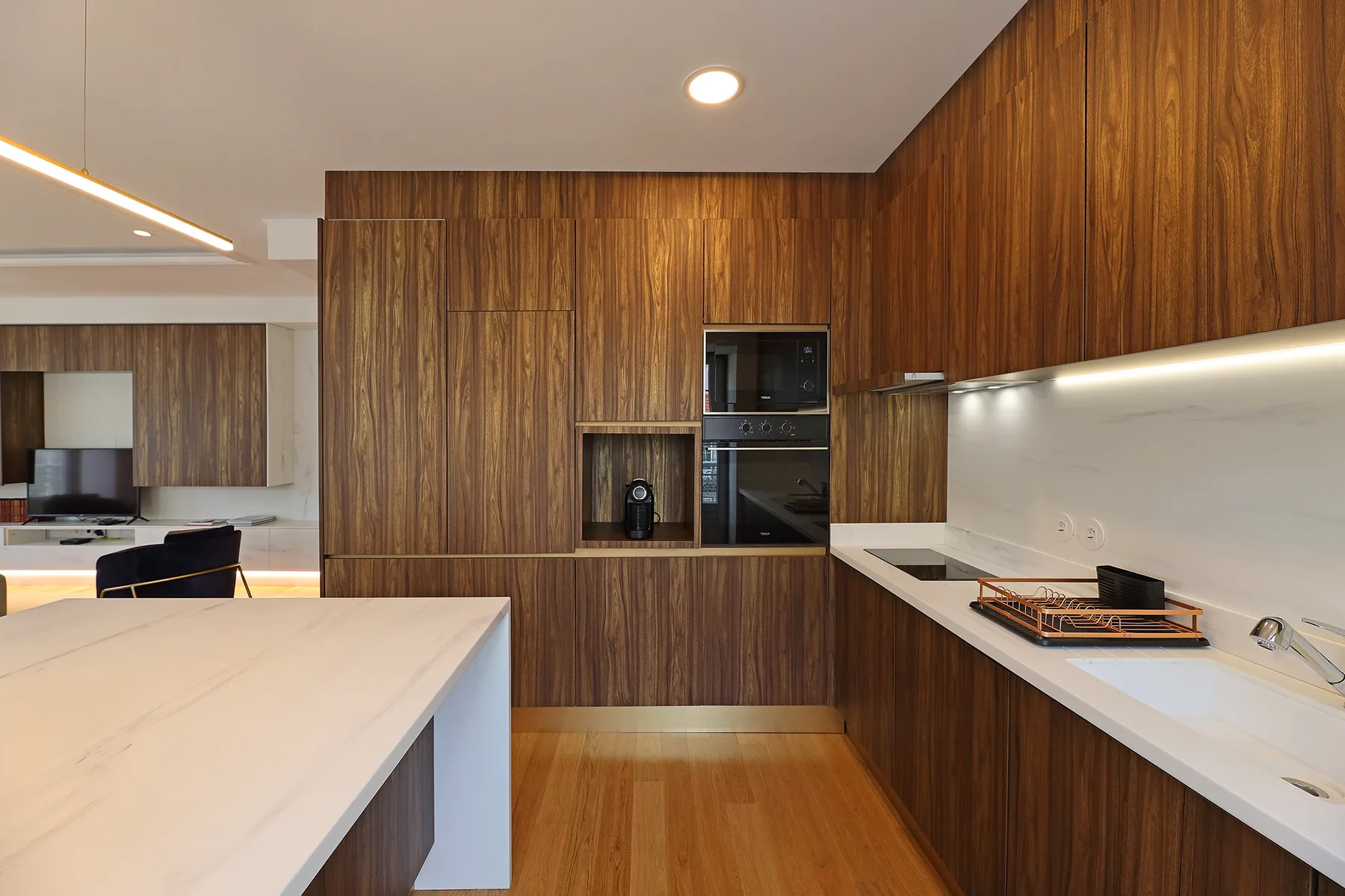 Una cocina moderna con gabinetes de madera, electrodomésticos integrados y encimeras claras.