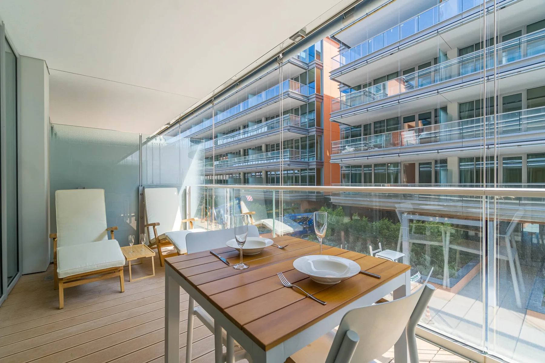 A dining table and seating overlook neighboring buildings through floor-to-ceiling windows.