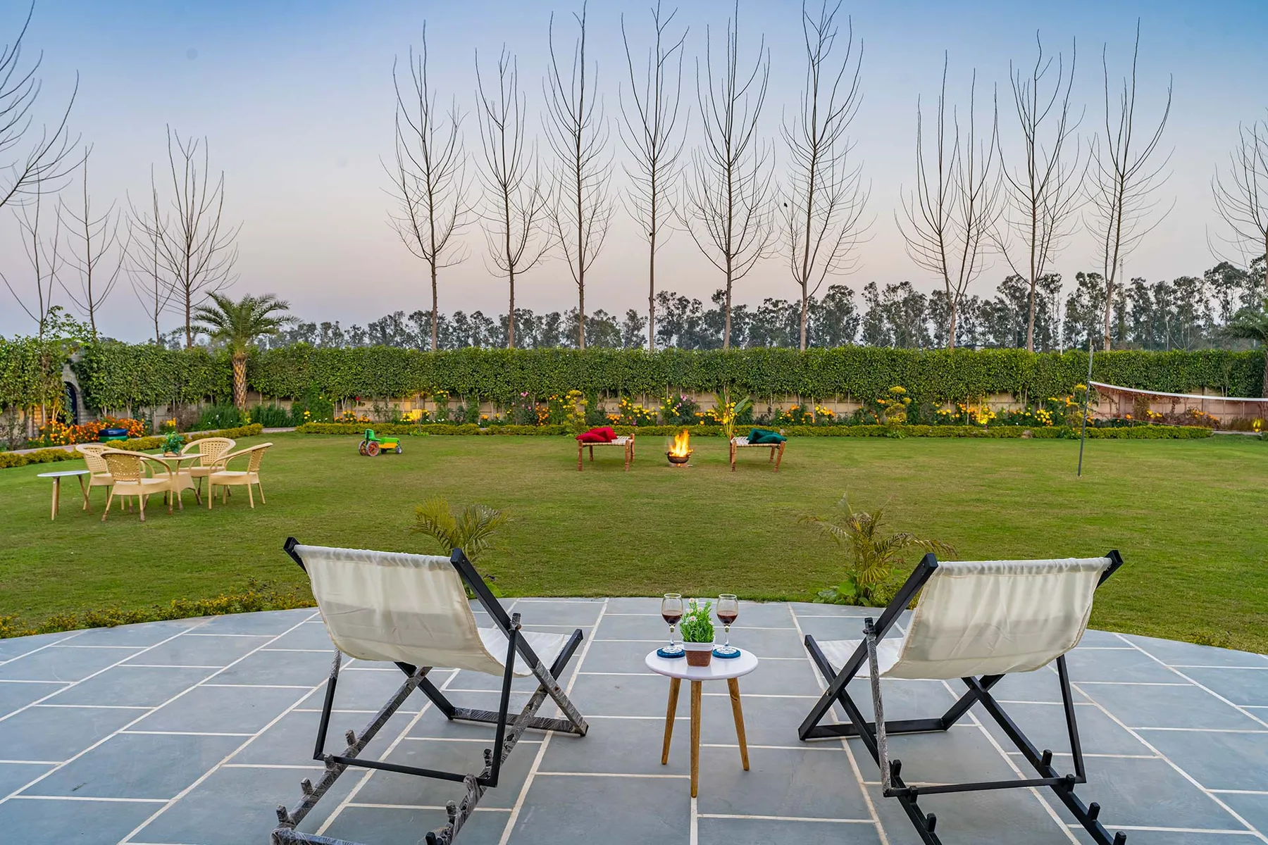 Una zona de estar en el patio da a un césped verde y un jardín ajardinado.
