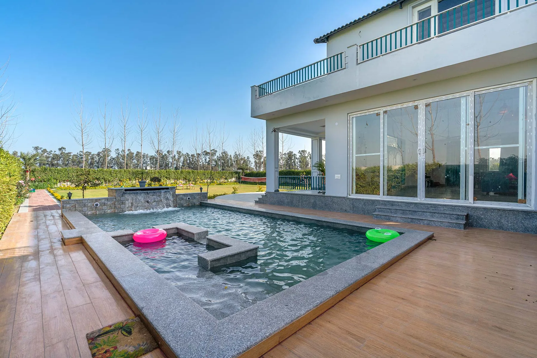 Una casa moderna da a una piscina exterior rectangular y una terraza de madera.