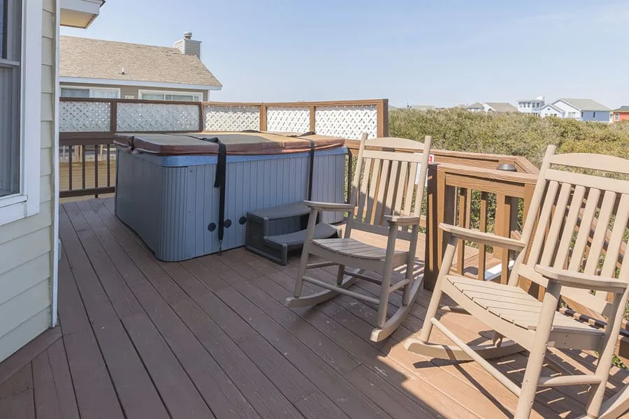 Una terraza exterior con una bañera de hidromasaje y asientos de madera da al paisaje.