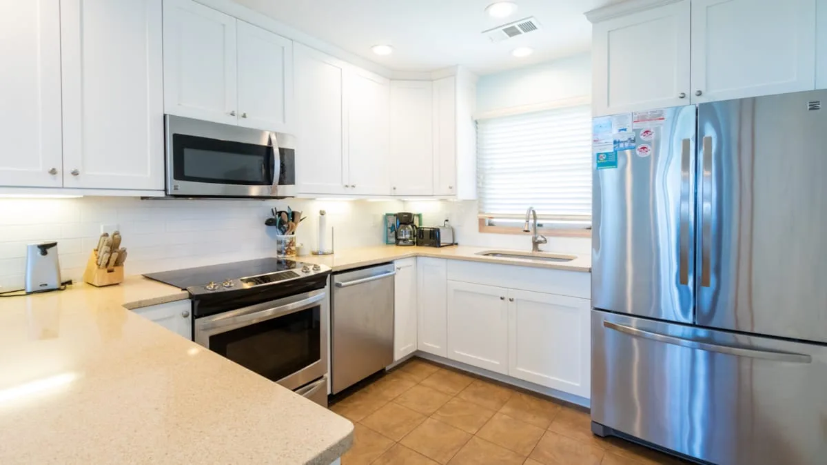A bright kitchen with white cabinets, stainless steel appliances, and a central island.