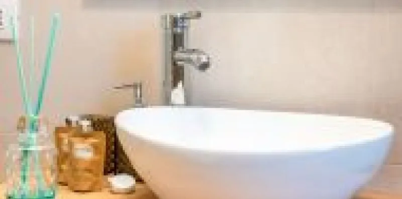 Un lavabo de baño presenta un fregadero blanco sobrepuesto y un grifo cromado.