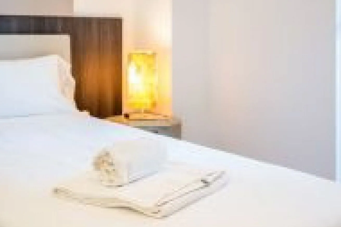 Un dormitorio con una cama bien tendida y una lámpara de noche.