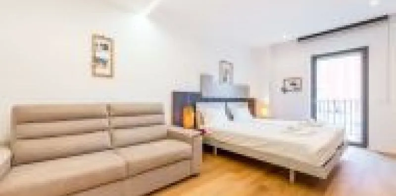 A bedroom with a bed, a sofa, and a glass door.