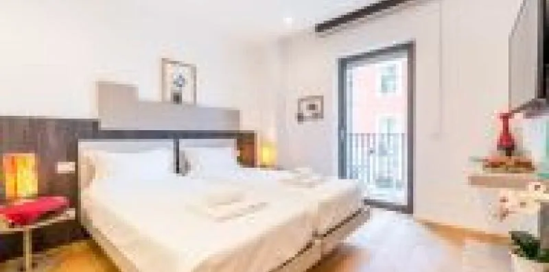 A bedroom with a bed beside a glass door opening to a balcony.