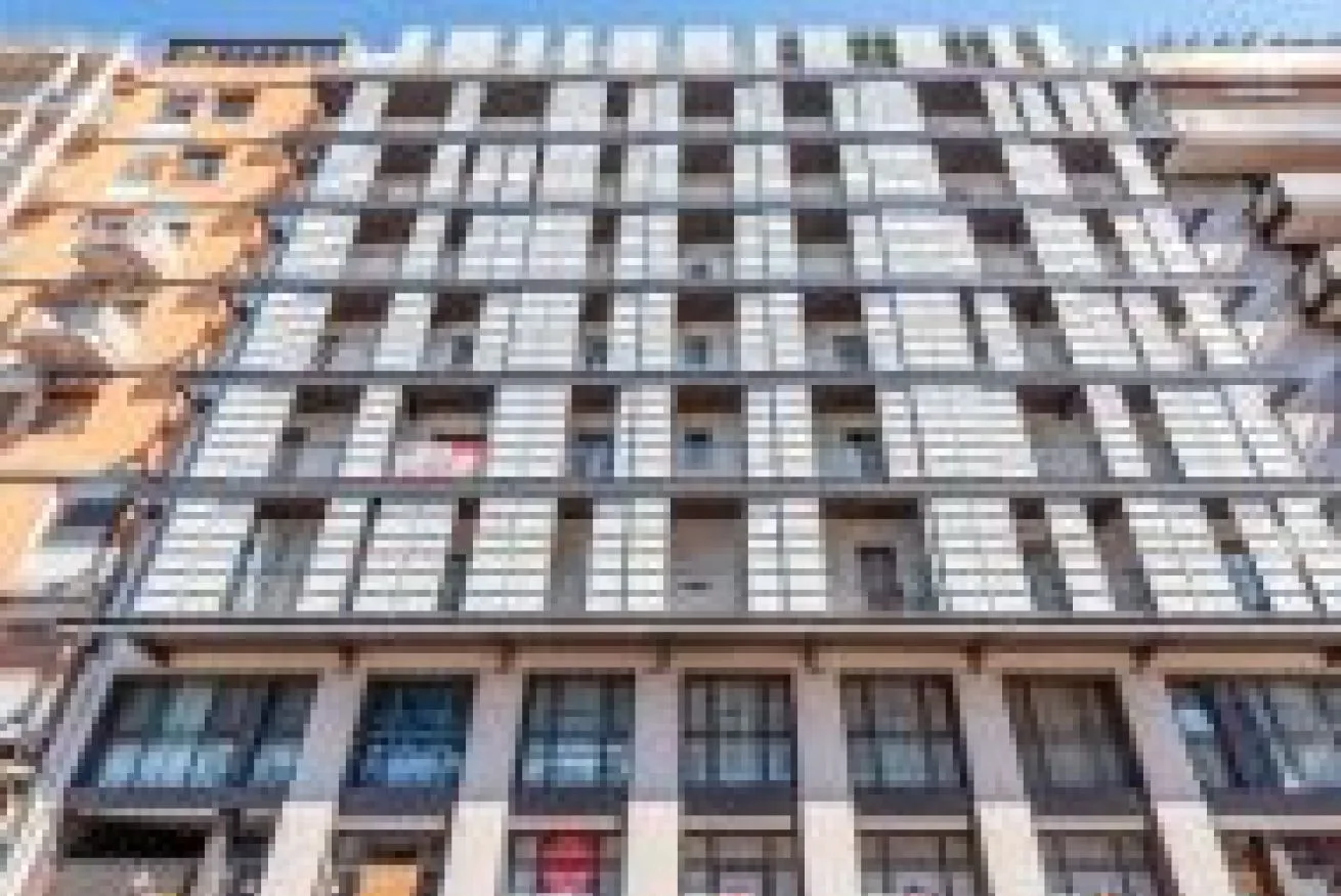 La fachada de un edificio de varias plantas con filas de ventanas y balcones.