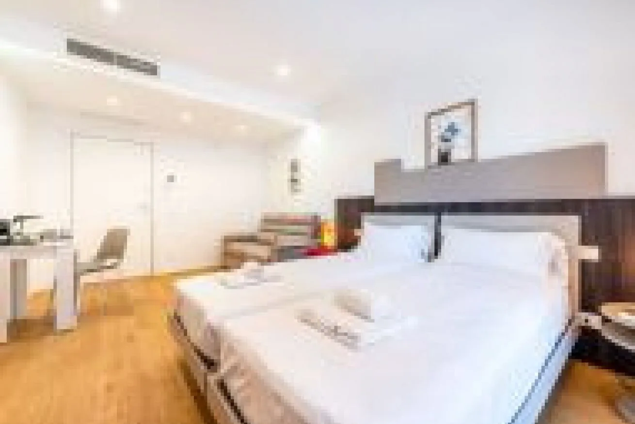 Un dormitorio luminoso con una cama grande y un escritorio junto a la pared.