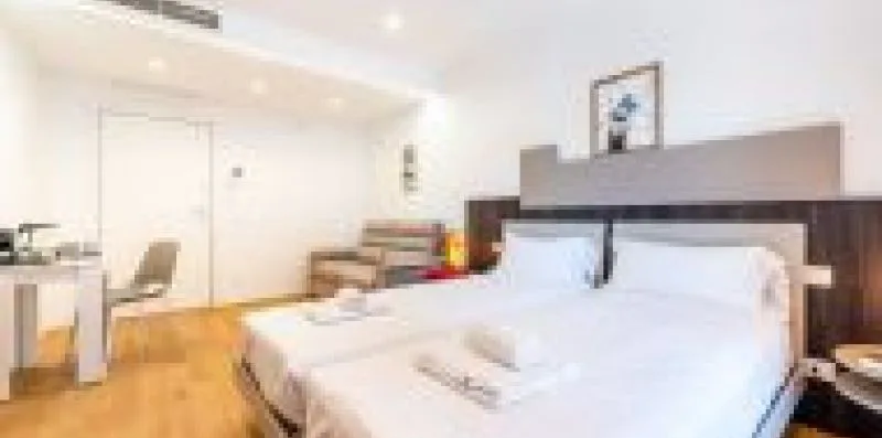 Un dormitorio luminoso con una cama grande y una pequeña zona de estar.
