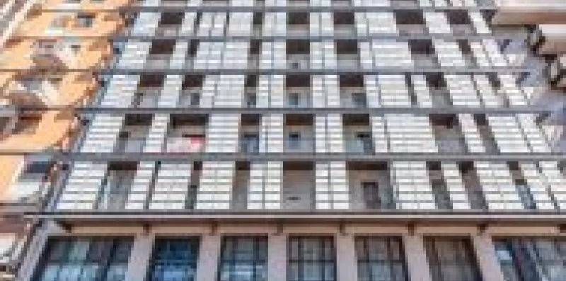 Fachada de un edificio de varias plantas con filas de ventanas y balcones.