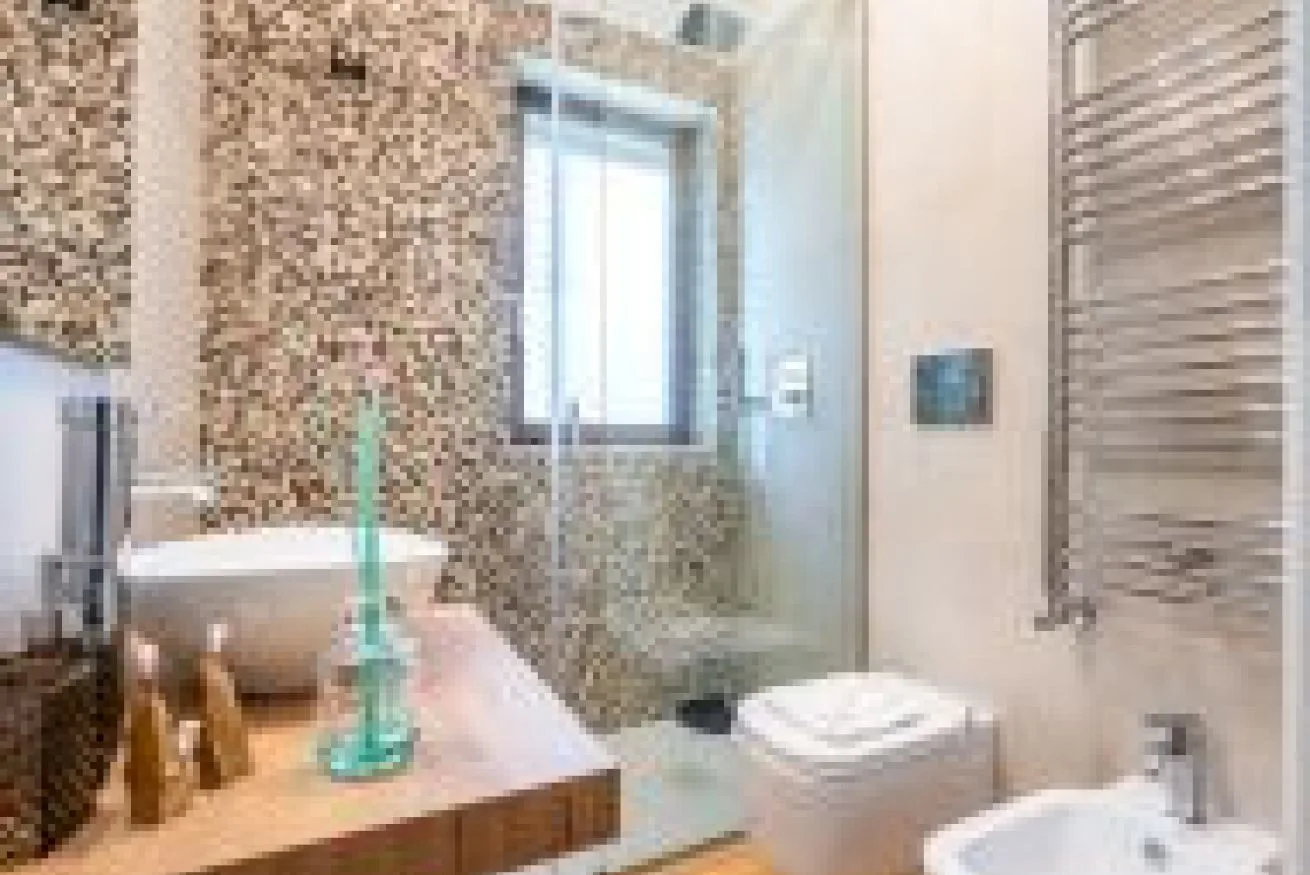Un baño con una pared de azulejos, un lavabo y accesorios de baño.