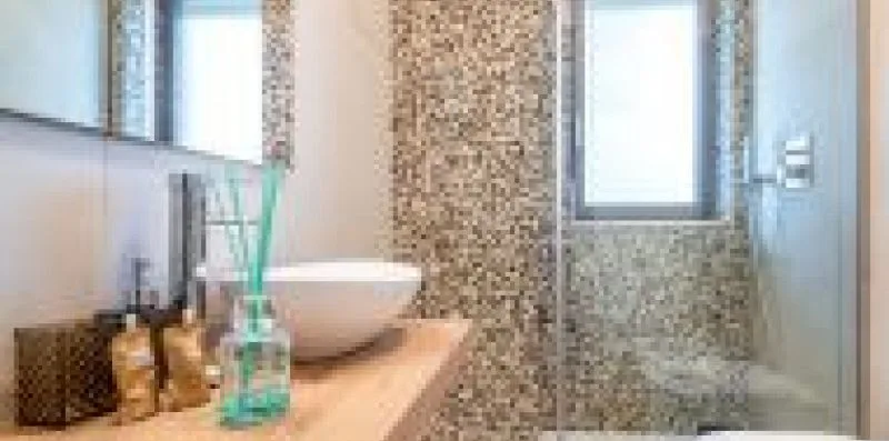 A bathroom vanity with a vessel sink and a tiled shower area.