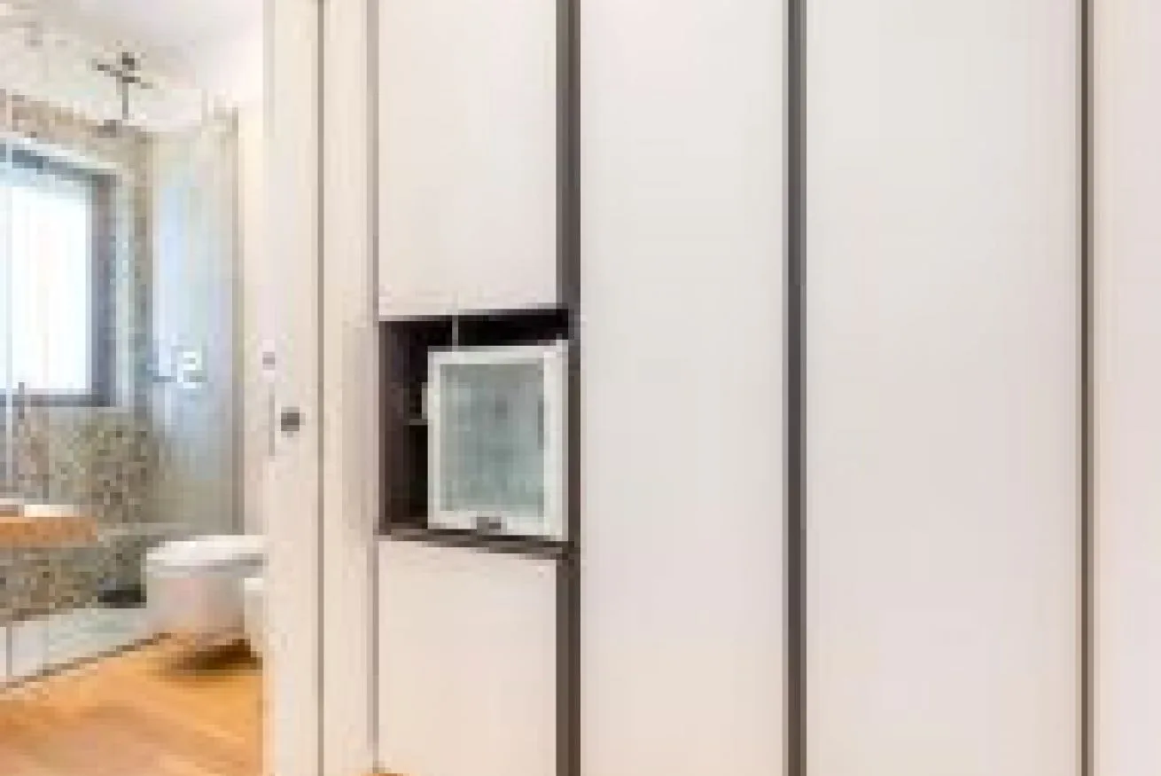 Un baño con un inodoro y una ducha acristalada junto a un armario de pared.