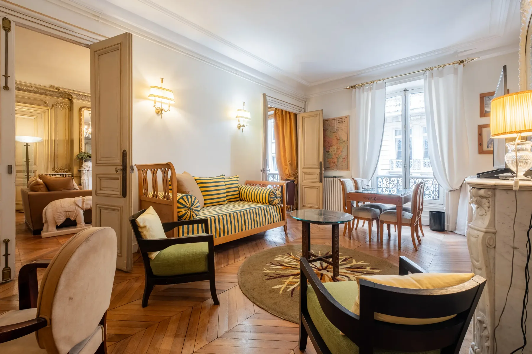 A furnished living room with striped seating and tall windows.