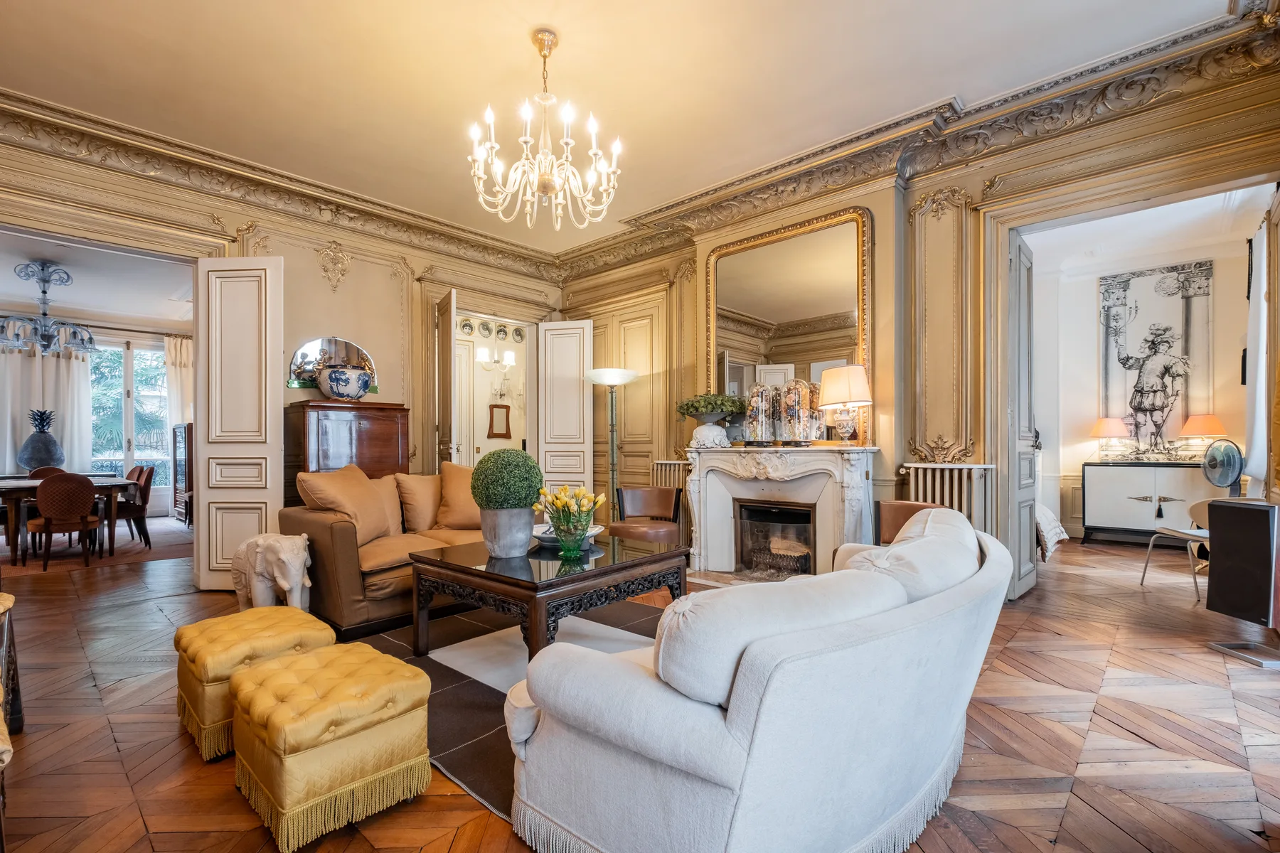 An ornate living room with seating arranged around a fireplace.