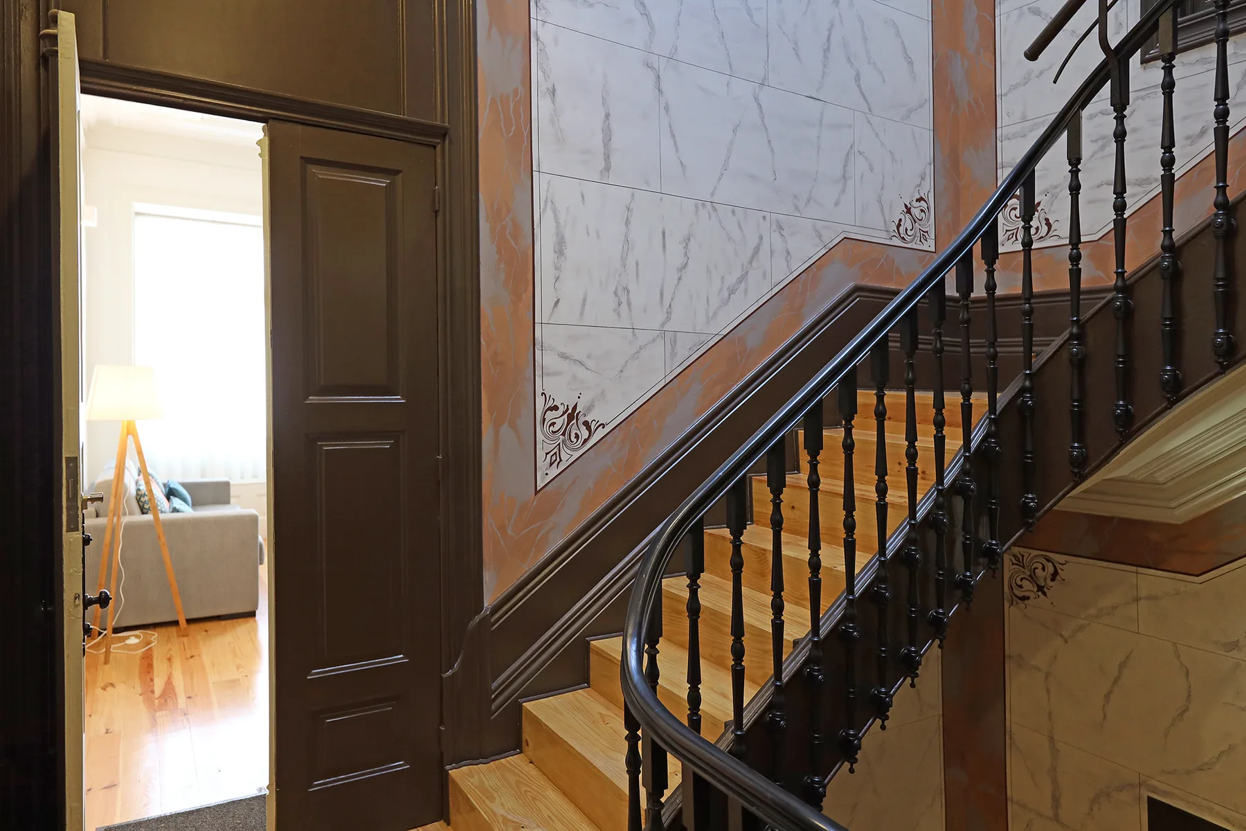 A wooden staircase with dark railings rises beside an open doorway.